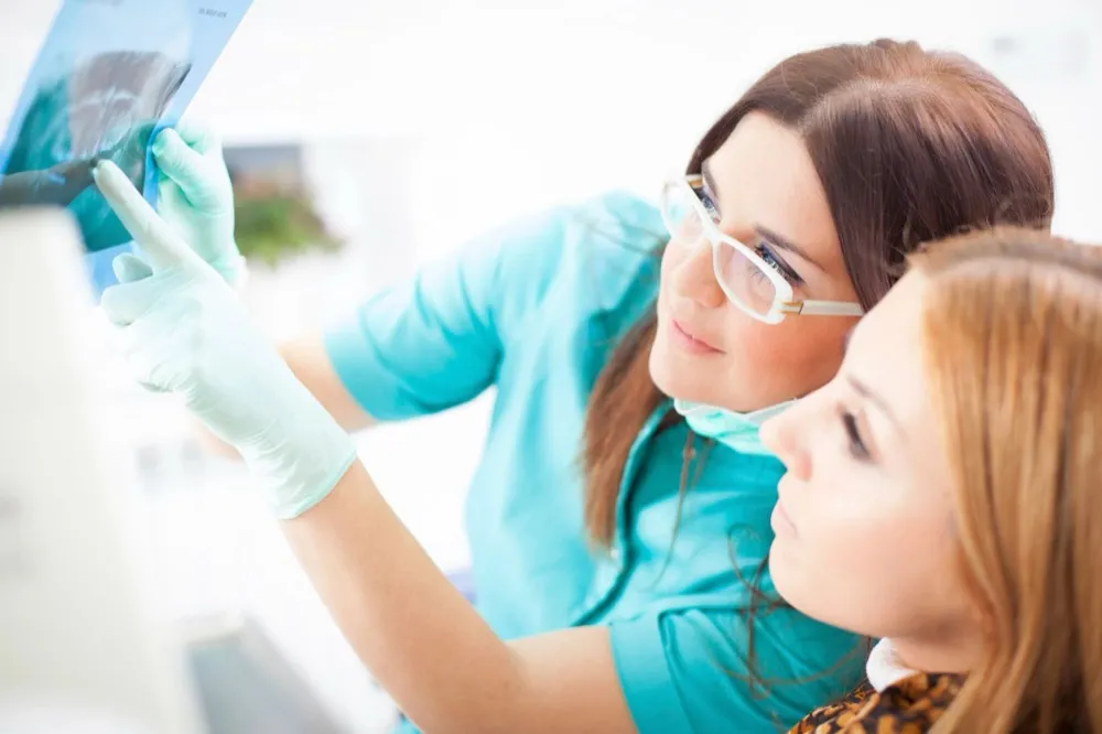 A dental professional reviewing an x-ray with a patient